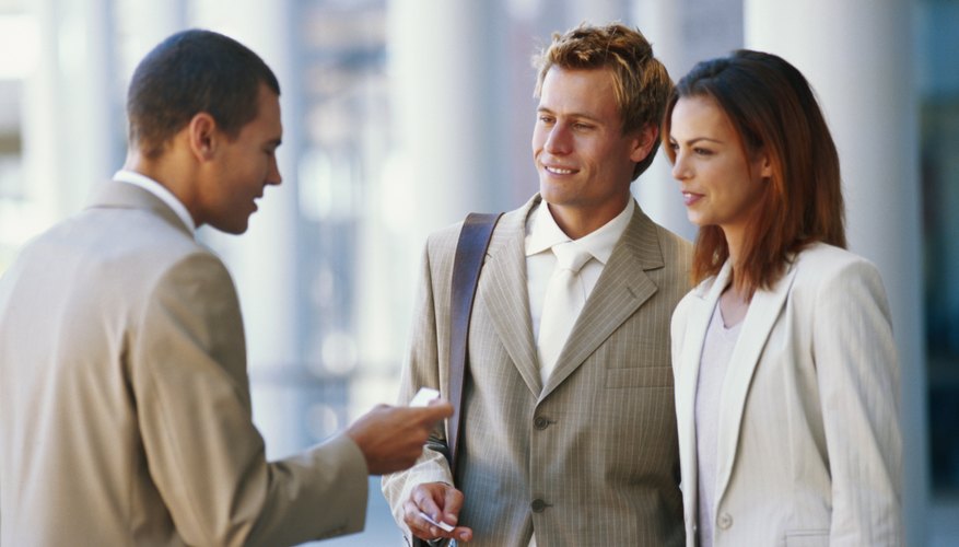 Two businessmen and women exchanging business cards