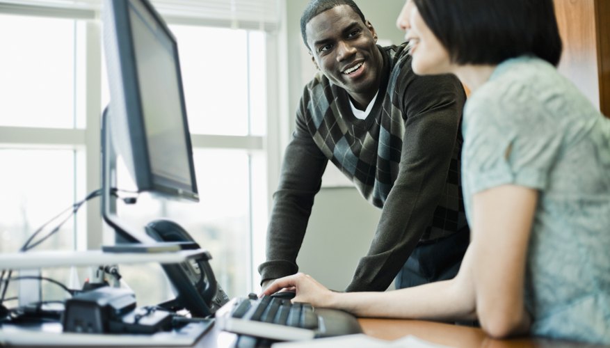 Photo Credit: Fuse/Fuse/Getty Images A man works with a woman at an office work station.