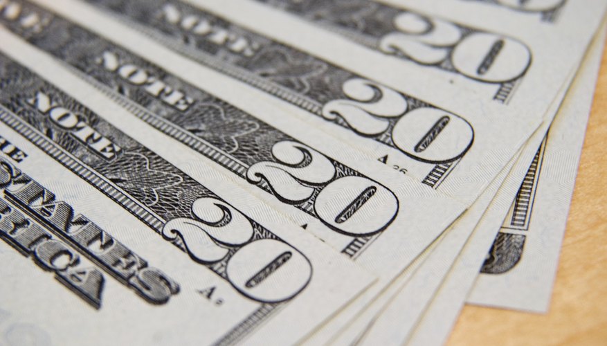 Close-up of twenty dollar bills fanned out on a table.