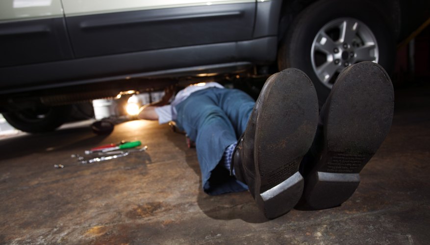Feet of mechanic working under SUV