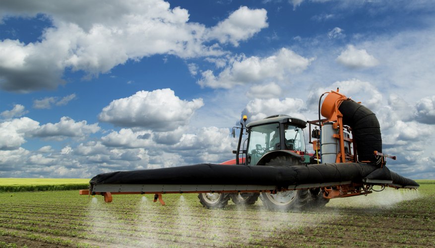 Spraying soybean field at spring over amazing cloudscape