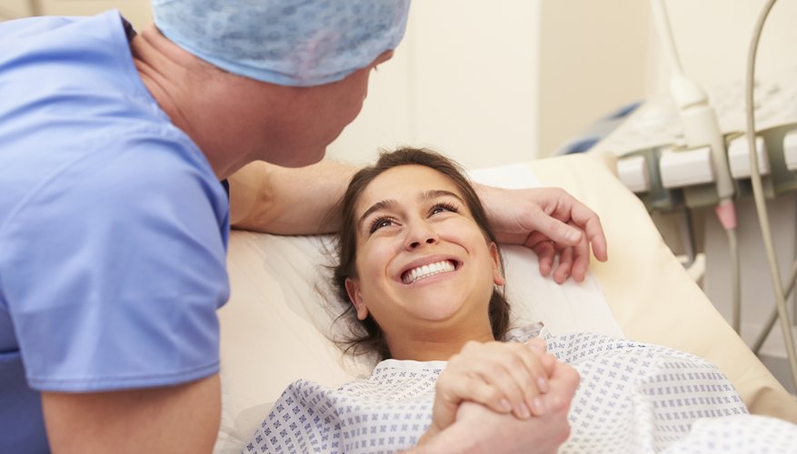Pregnant woman holding husband's hand during delivery Pregnant woman holding husband's hand during delivery