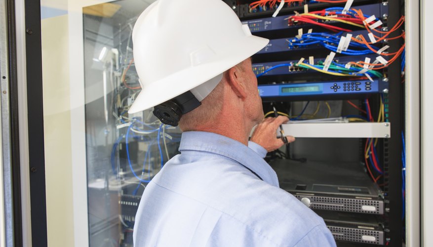 Engineer at electric power plant control room looking at servers and switches