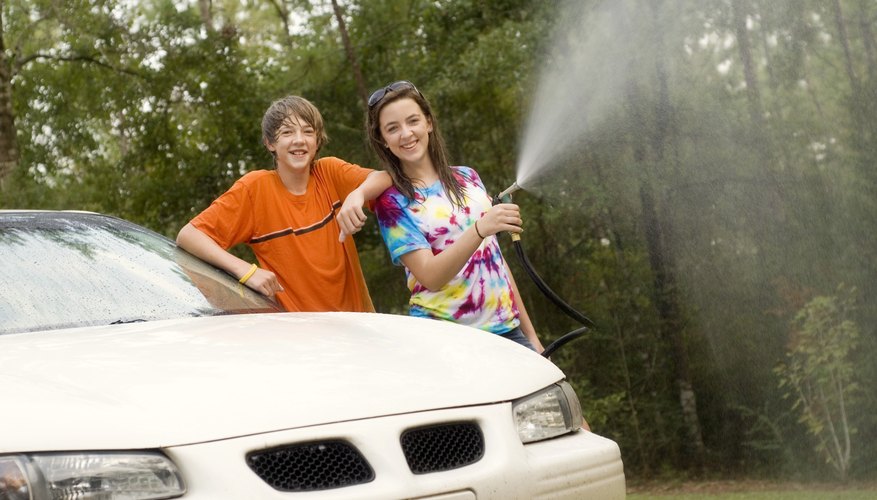 Two teenaged siblings washing a car together. Two teenaged siblings washing a car together.