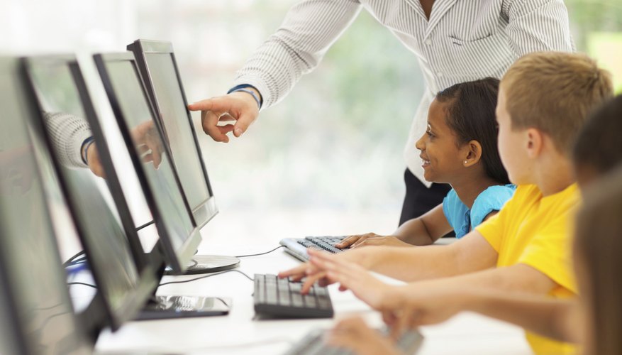 A teacher works with students in a school computer lab. A teacher works with students in a school computer lab.