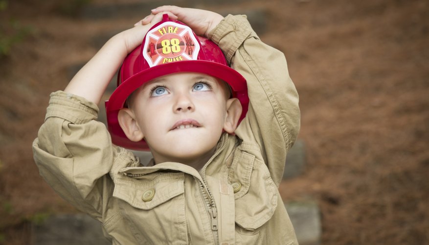 A little boy dressed as a fireman looking up at a tree. A little boy dressed as a fireman looking up at a tree.