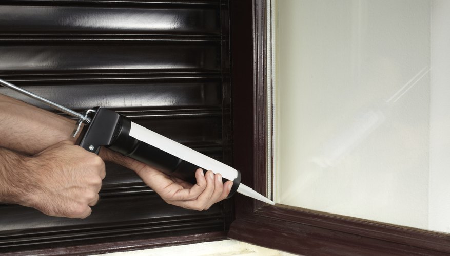 Photo Credit: AndreaAstes/iStock/Getty Images Close-up of a workman applying sealant to a window pane