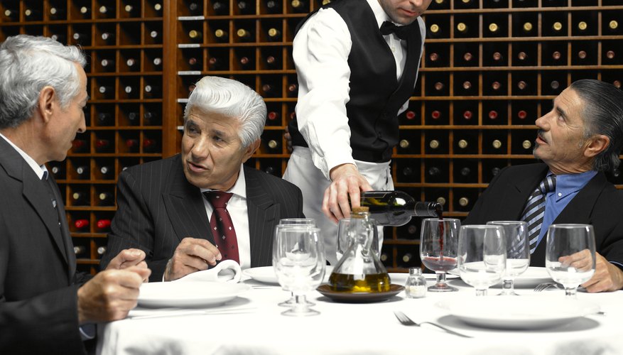 Waiter serving wine to businessmen in restaurant