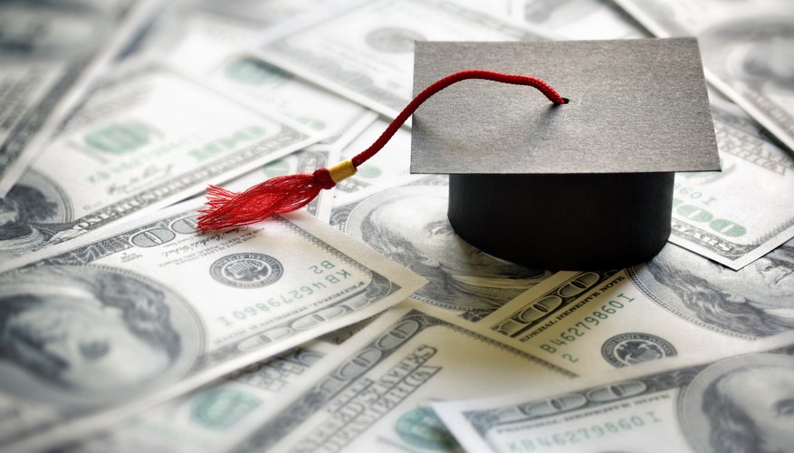 A paper mortar hat model sitting on one hundred dollar bills.