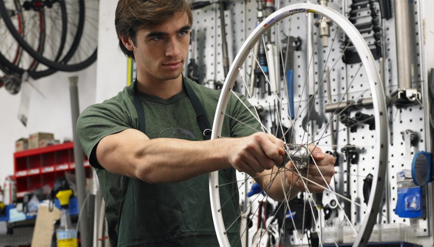 Young man holding wheel of bicycle in shop
