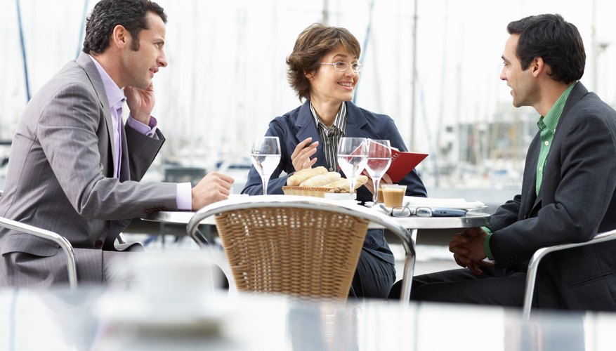 Three business people outdoors at table in restaurant