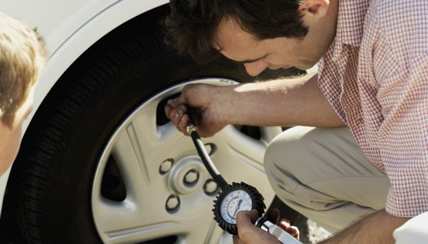 high angle view of a young man checking the air pressure of a car tire