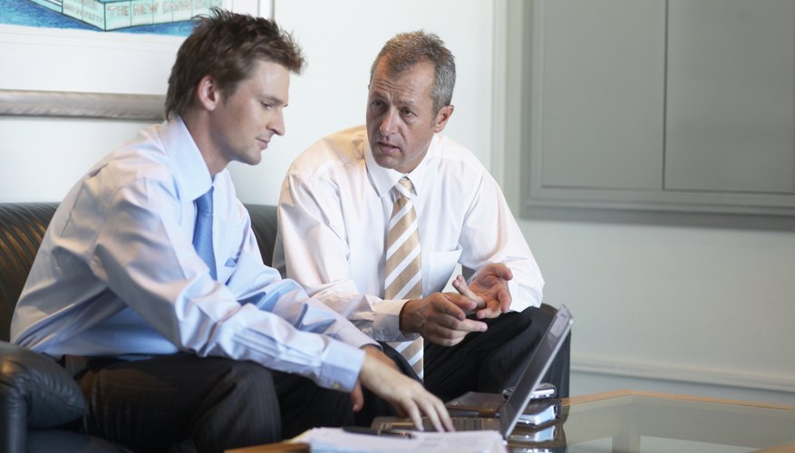 Two businessmen having discussion on sofa in office waiting area