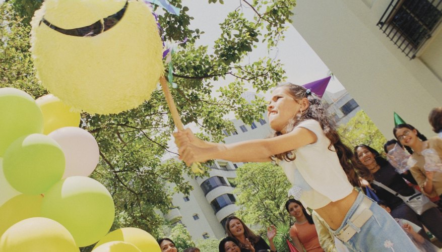 Niña rompiendo una piñata en una fiesta infantil.