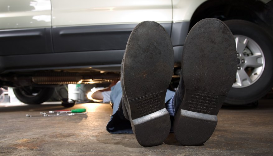 Feet of mechanic working under SUV
