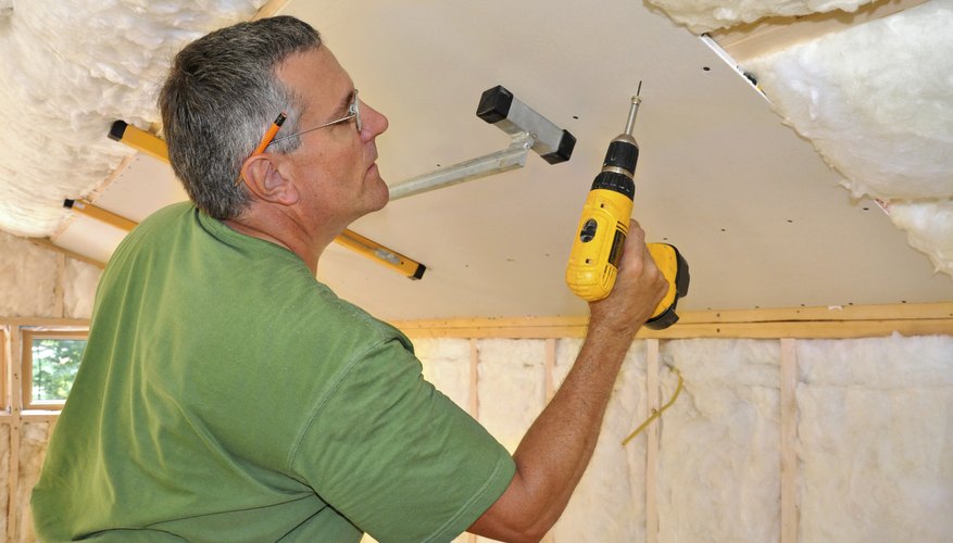 Man installing drywall into ceiling Man installing drywall into ceiling