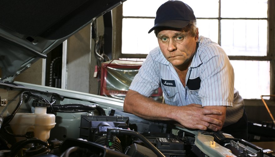 Stumped mechanic leaning over engine compartment