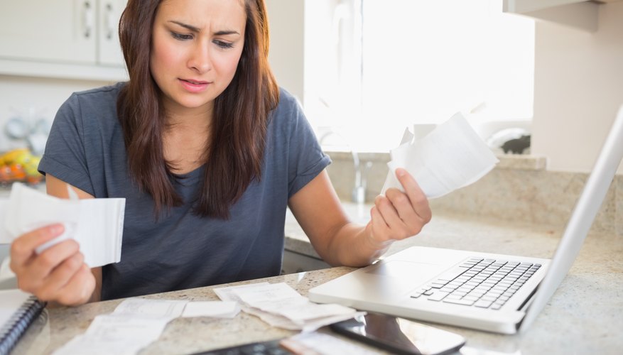 A woman paying bills at the kitchen table.