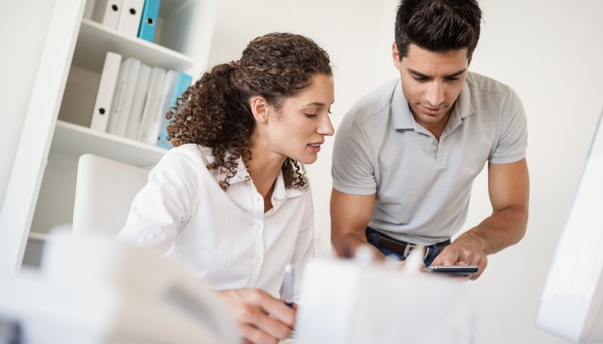 Casual business team looking at calculator together