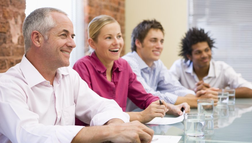 Four businesspeople in boardroom smiling