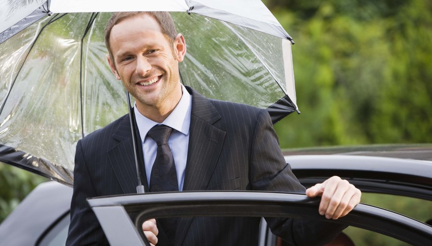Man holding umbrella by car