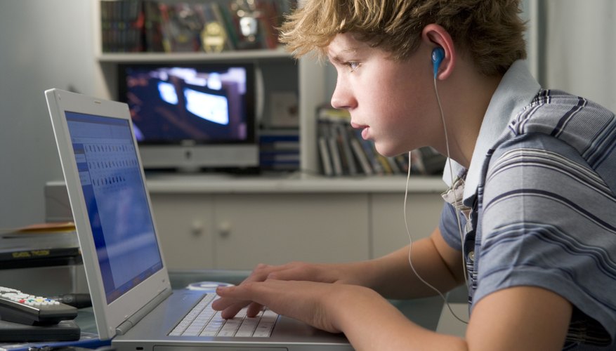 Photo Credit: Monkey Business Images/Monkey Business/Getty Images Teenage boy working on computer with headphones.