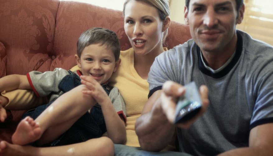 Portrait of a mid adult couple watching television with their son