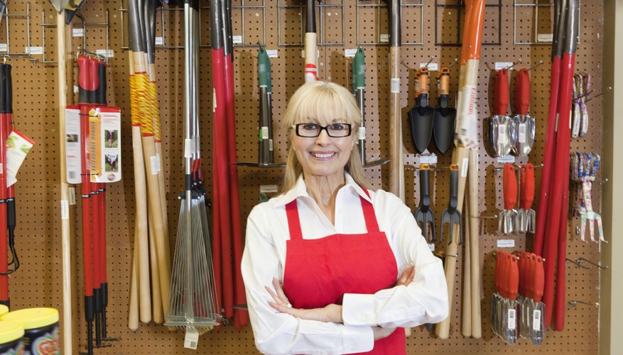 Portrait of a happy senior woman with arms crossed in front of gardening tool