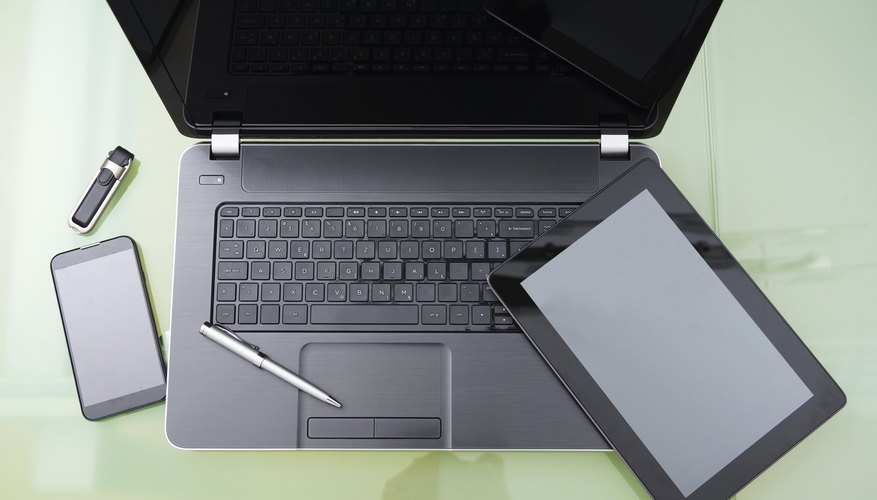 laptop with tablet and smart phone on glass table