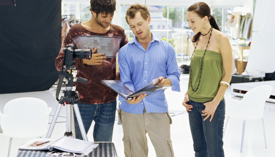 Two young men standing with a young woman and looking at a portfolio