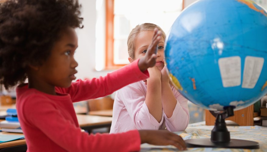 Two students looking at a globe on a table in the classroom. Two students looking at a globe on a table in the classroom.