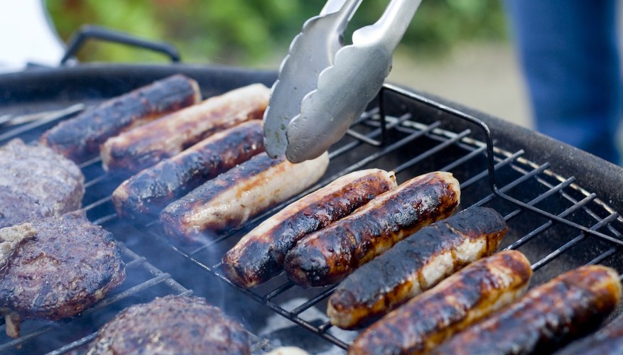 Close-up of tongs being used to handle sausages on a BBQ grill Close-up of tongs being used to handle sausages on a BBQ grill