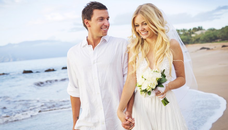 Photo Credit: EpicStockMedia/iStock/Getty Images Newlywed couple walking on Caribbean beachfront