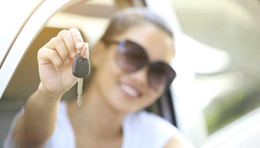 Young woman holding a key to a new car.