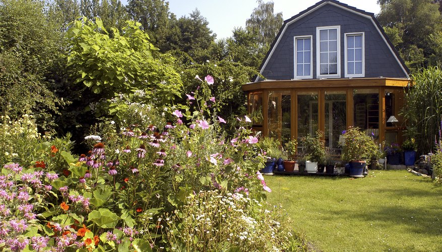 The backyard and garden of a home with a sunroom addition.