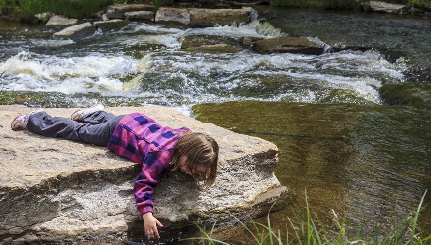 Photo Credit: Jim_Pintar/iStock/Getty Images This young girl is studying a stream.