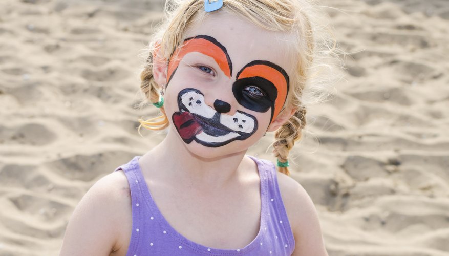 A girl with a painted face playing in the sand. A girl with a painted face playing in the sand.