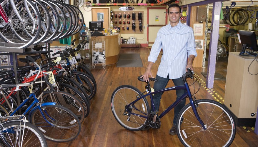 Proud business owner standing with bicycle in bike shop