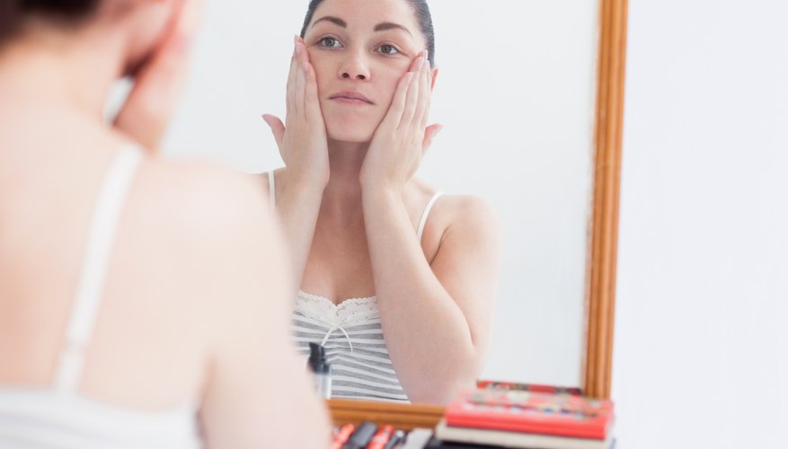 A woman applies moisturizer to her face. A woman applies moisturizer to her face.