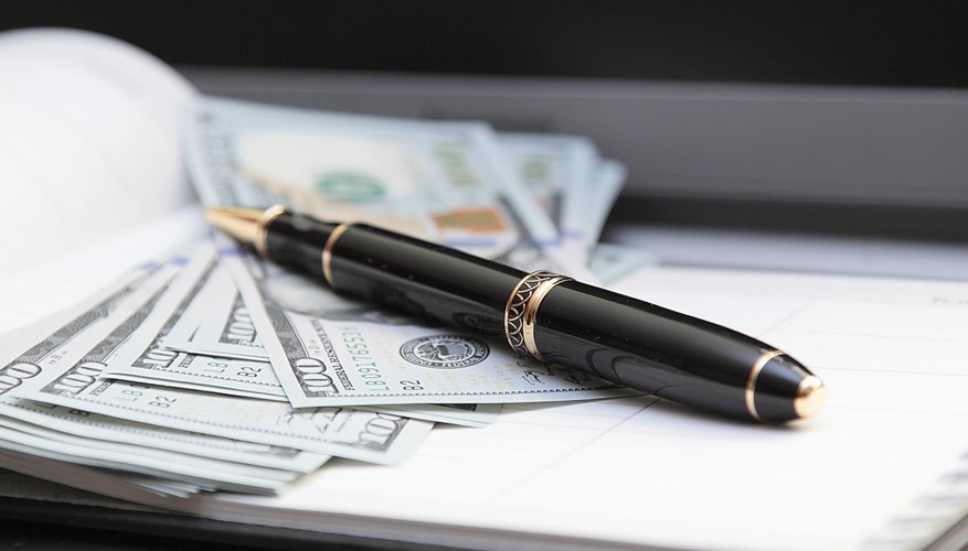 A close-up of an ink pen on top of bank notes.