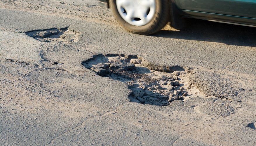 Car passing a large pothole.
