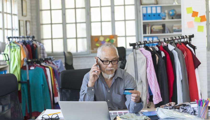 Mature man in fashion studio using credit card