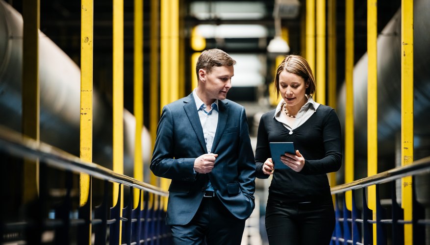 Two Business Person Walking A Dark Factory Hallway