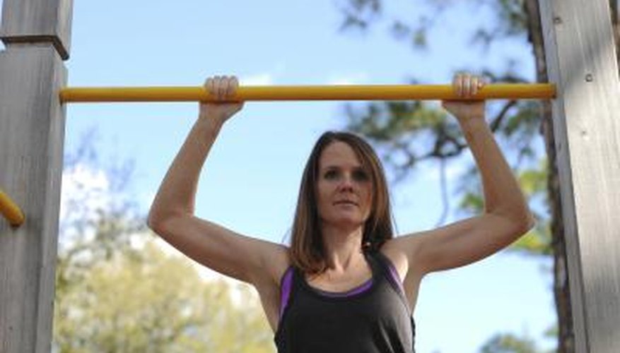 A woman is doing pullups outdoors. A woman is doing pullups outdoors.