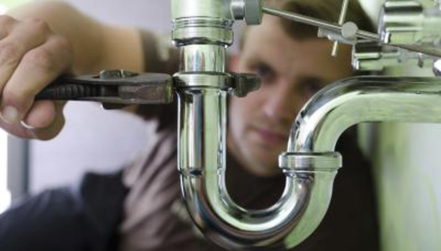 A man tightens a pipe with a wrench. A man tightens a pipe with a wrench.