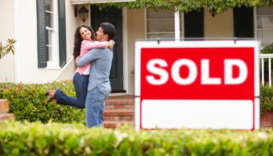 Couple hug in front of sold house