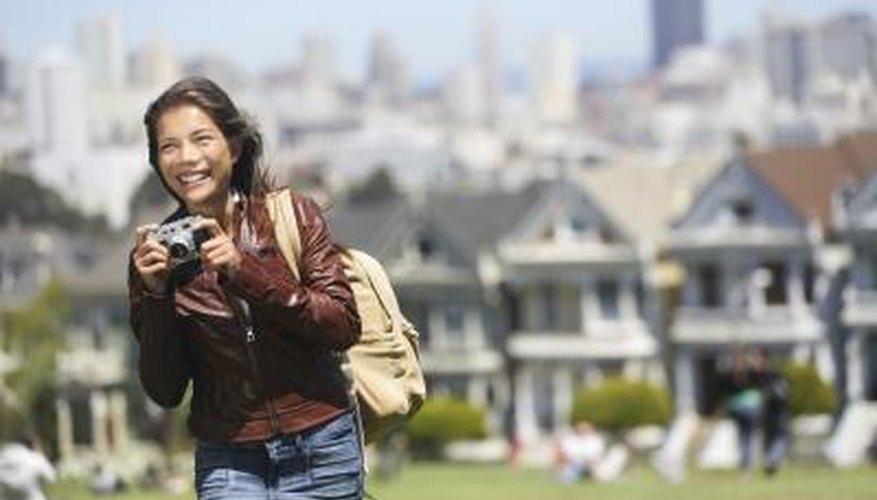 A woman with a camera walks through a neighborhood with Victorian homes. A woman with a camera walks through a neighborhood with Victorian homes.