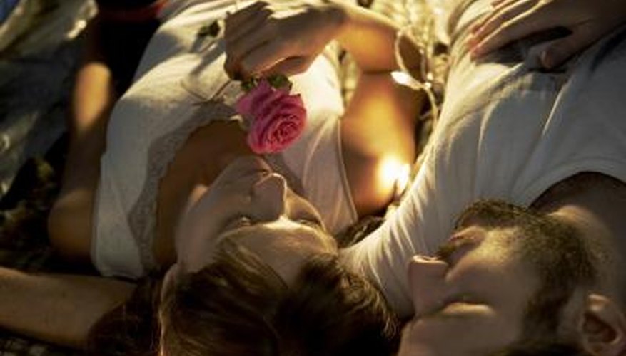An overhead view of a woman smelling a rose while snuggling with her romantic boyfriend. An overhead view of a woman smelling a rose while snuggling with her romantic boyfriend.