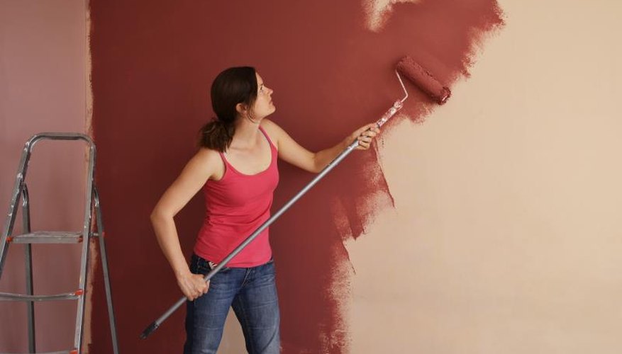 Woman using roller to paint wall Woman using roller to paint wall