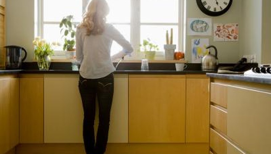 A woman stands at the sink in a kitchen. A woman stands at the sink in a kitchen.